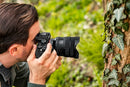 A professional photographer using the Tamron 12-20mm ultra-wide lens on a Sony mirrorless camera.