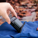 A hand sliding the ultra compact KingMa Canon NB-2LH battery charger directly into a travel backpack mesh accessory pouch.