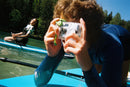 Person taking a picture underwater on a paddleboard using the FUJIFILM QuickSnap Active camera from Best Camera Store.