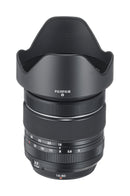 Straight side profile view of the Fujifilm XF 16-80mm f-4 R OIS WR lens with the petal lens hood securely attached facing left