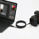 A professional photography workspace displaying the KingMa USB-C cable actively tethering a black mirrorless camera system to an open laptop running a digital photo editing desktop software workspace.