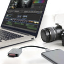 Optex OR1000 UHS-II memory card reader connected to a smartphone alongside a laptop running video editing software next to a professional DSLR camera lens.