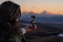Person filming a mountainous landscape with a Insta360 luna pocket  camera stabilizer at sunset.