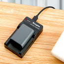 KingMa compact battery charger on a wooden desk showing a red illuminated LED status indicator light for an active power stream.