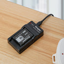 KingMa compact battery charger on a wooden surface showing a red illuminated LED status light indicating active charging power.