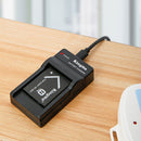 KingMa compact battery charger on a wooden desk showing a red illuminated LED status indicator light for active charging.