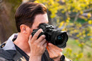 Close-up of a photographer’s hands holding a Nikon Z series camera mounted with the Tamron 12-20mm F2.8 lens in warm golden hour light, from Best Camera Store.