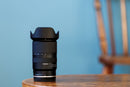 Tamron 17-70mm f2.8 Nikon Z mount lens standing upright on a table with the flower-shaped hood attached.