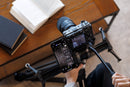 A smartphone showing the Tamron Lens Utility Mobile app wirelessly connected to a camera lens via the TL-01 adapter.
