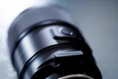 The compact TAMRON-LINK TL-01 adapter plugged into the USB-C port of a Tamron lens for wireless control.