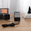 Close-up demonstration showing the KingMa 16.8V 3A single power supply actively connected to a cinema V-Lock battery pack on a desk.